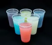 Seven colorful drinks in clear plastic cups on a black background.