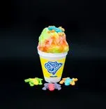 A colorful shaved ice in a Sno Biz cup topped with gummy bears, with more gummy bears scattered on a black background.