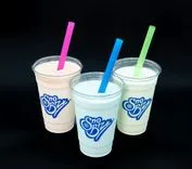 Three Sno Biz branded milkshake cups with pink, blue, and green straws against a black background.