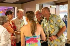 Group of people socializing at an indoor event, some wearing Hawaiian shirts.