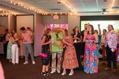 Group of people in colorful clothing gathered at an indoor event with a festive atmosphere.
