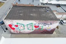 Aerial view of a building with a colorful mural on the sidewall featuring hearts and bicycles.