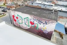 Aerial view of a colorful street art mural featuring various playing card suits on a building rooftop.